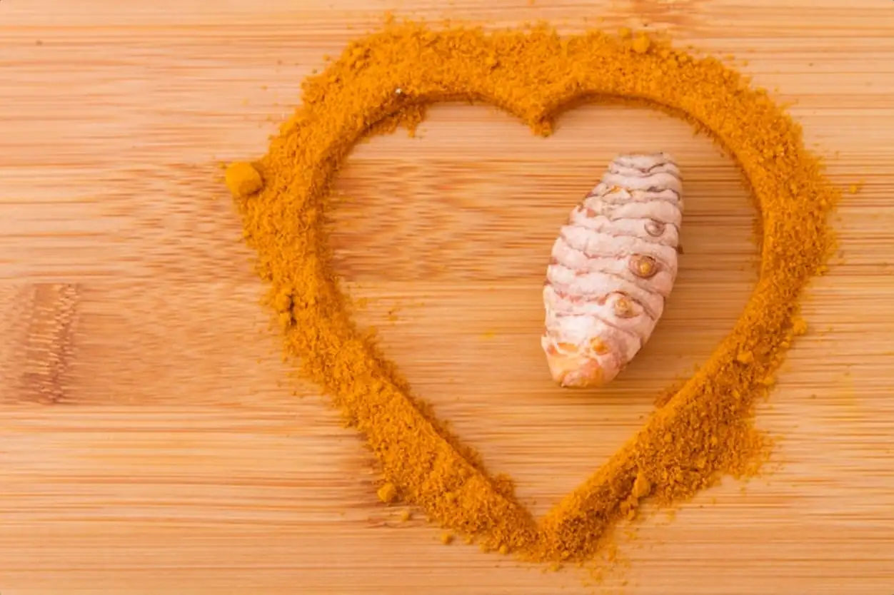 Turmeric powder and roots on wooden background