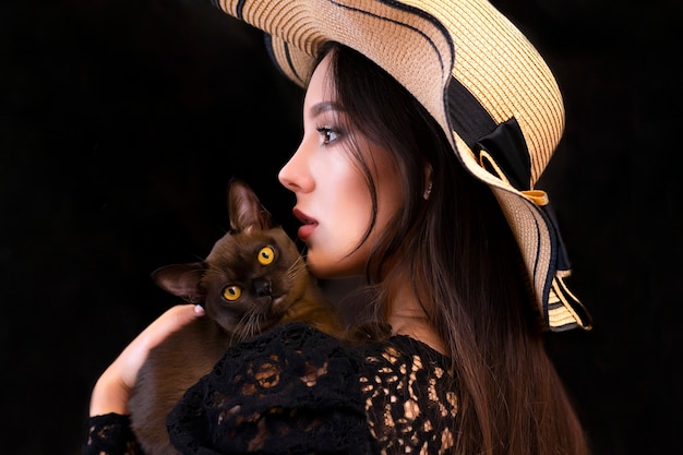 Young beautiful woman in a hat with cat in her hands