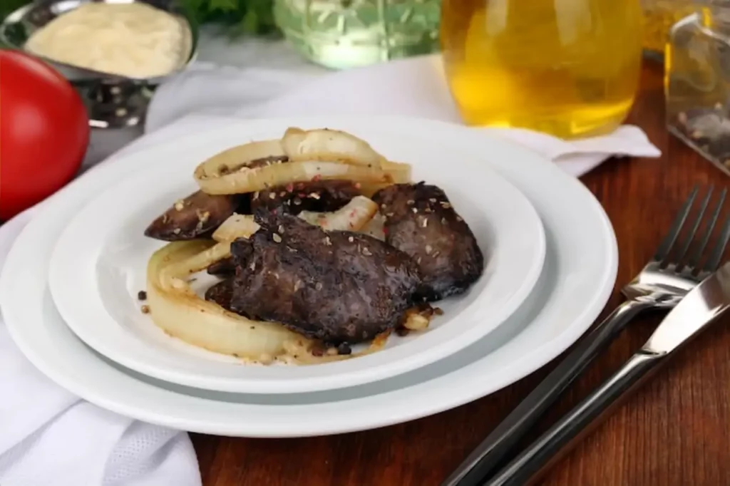 Fried chicken livers on plate on wooden table closeup