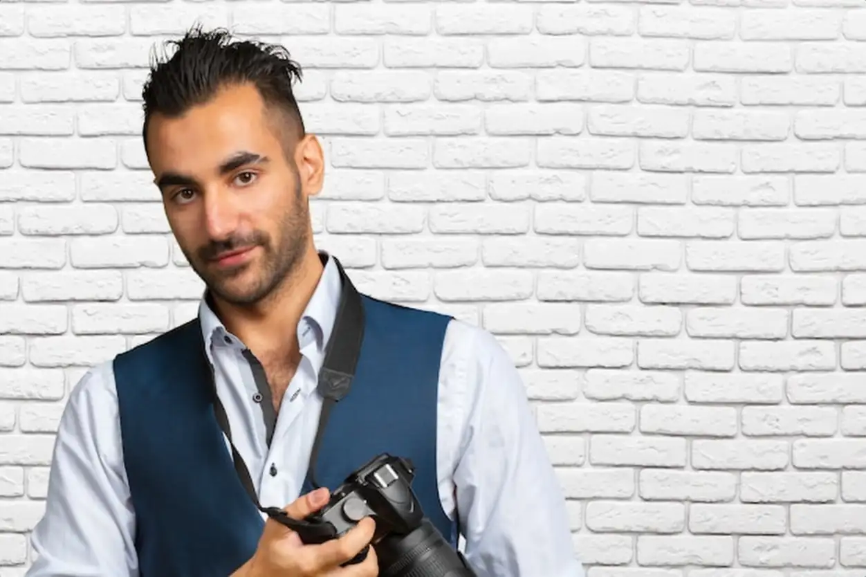 Young Arabian man using holding his camera ready to shoot, isolated
