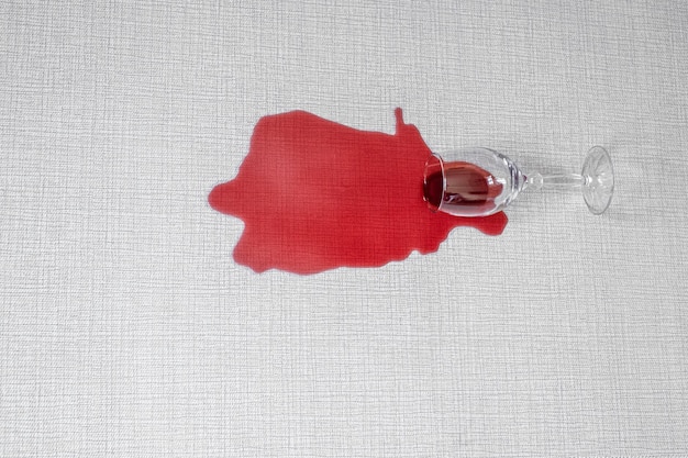 Red wine spilled near the sofa on a white carpet
