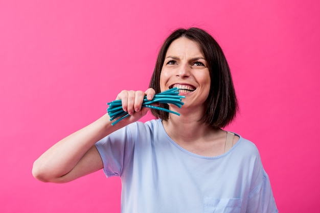 Young woman with sensitive teeth eating sweet candies on color background