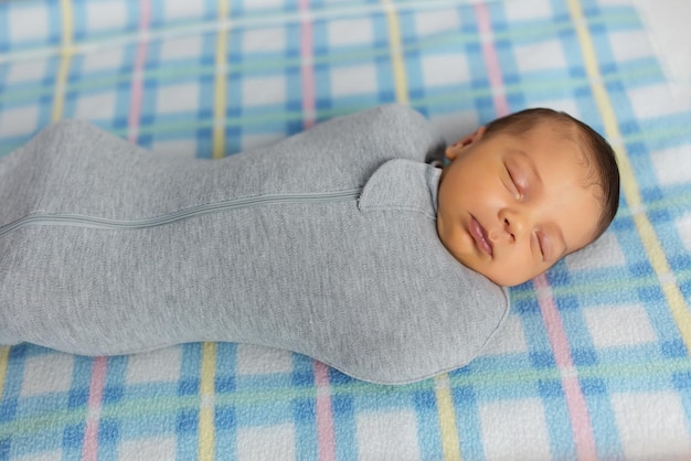 The baby is lying in a cocoon on cot He sleeps sweetly and dreams