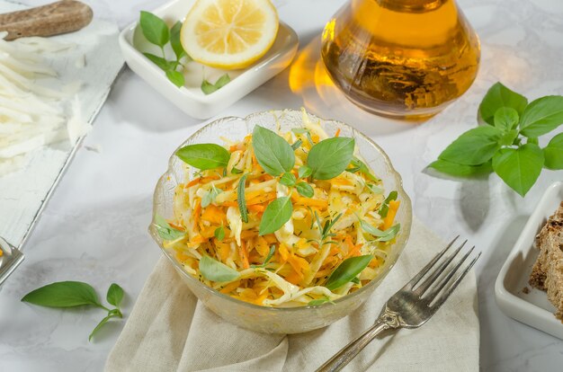 Cabbage salad, grated carrots and pumpkin with oil, basil and rosemary close-up