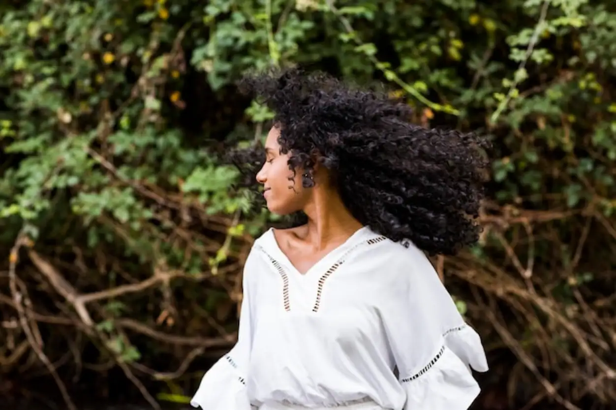 Young woman with eyes closed standing against trees