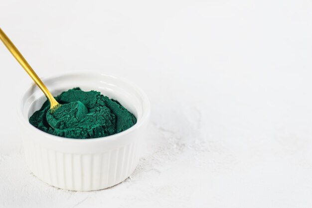 Close up of green spirulina powder in a spoon and a bowl