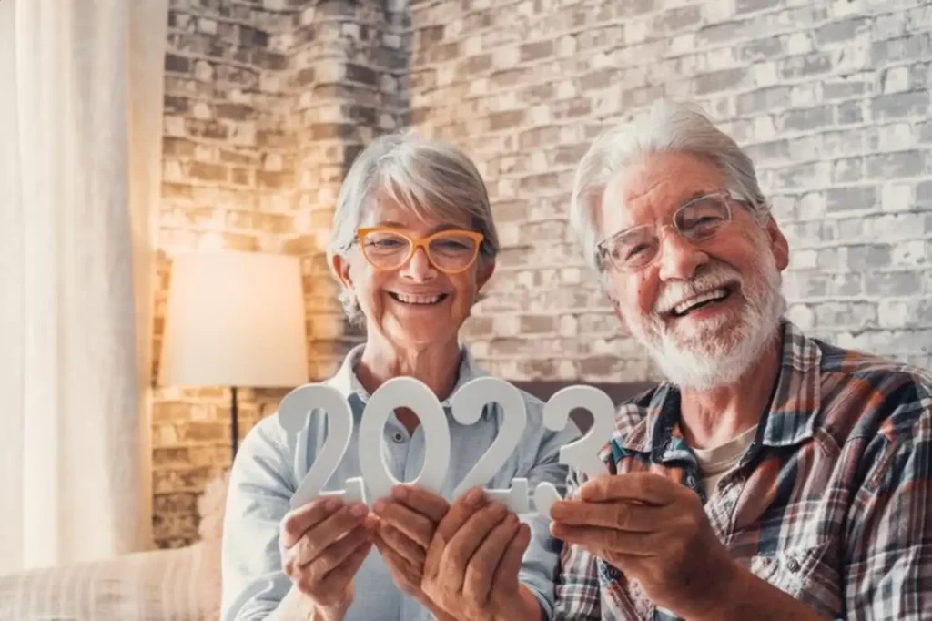 Portrait of couple of two old pensioners holding together numbers of 2023 at home Close up of new year numbers celebrating and goals for new life concept
