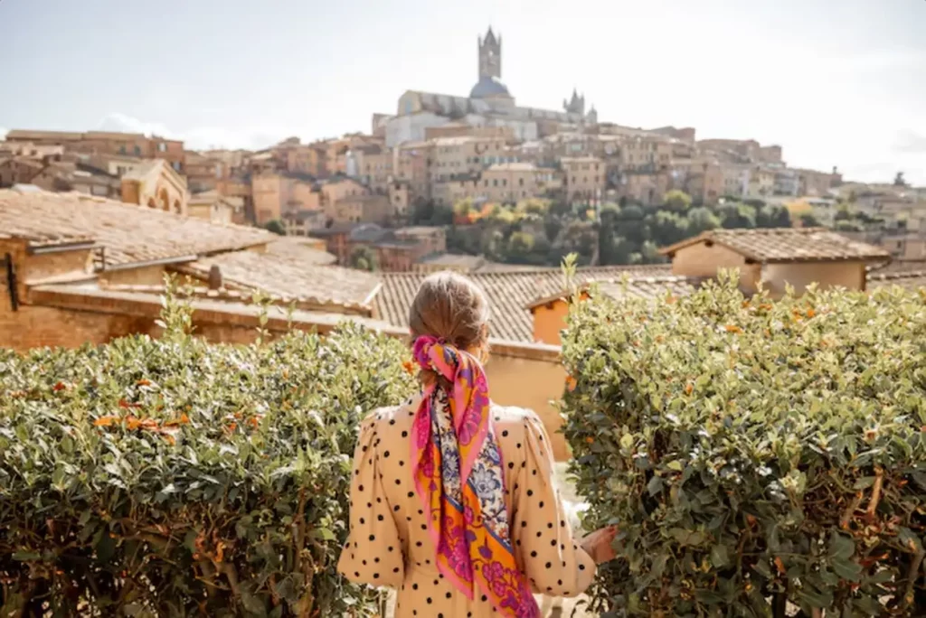 Woman walks on background of cityscape of siena old town in italy