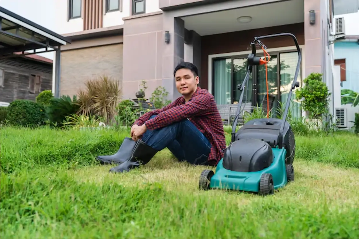 Young man sitting with a lawn mower for cutting grass at home