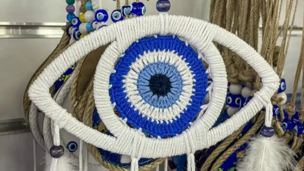 Handcrafted blue and white evil eye wall hanging with intricate crochet work surrounded by wrapped y