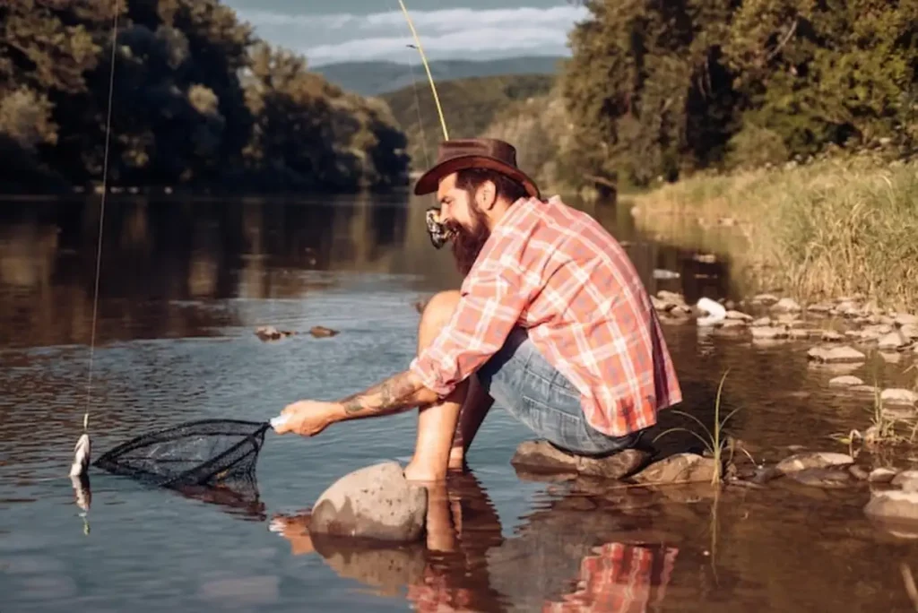 Man with fishing rod fisherman men in river water outdoor summer fishing hobby catching trout fish