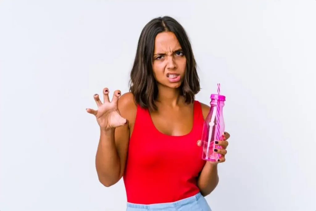 Young mixed race woman holding a milk shake isolated showing claws imitating a cat, aggressive gesture.