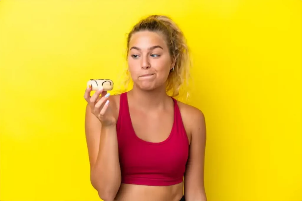 Girl with curly hair isolated on yellow background holding a donut