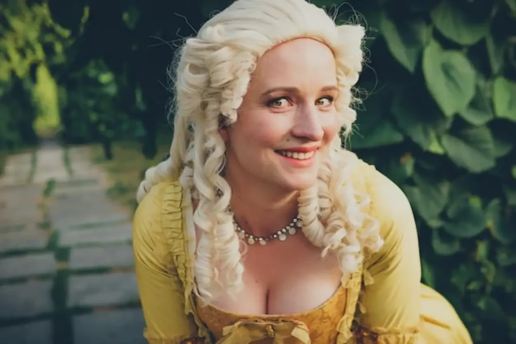 Portrait of blonde woman dressed in historical Baroque clothes with old fashion hairstyle outdoors