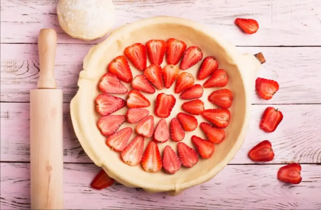Strawberries pie preparation on wooden table