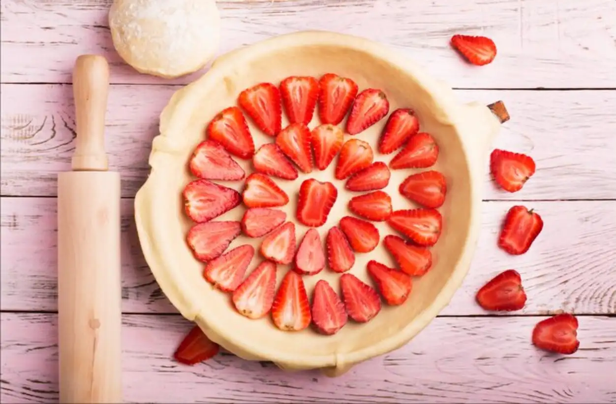 Strawberries pie preparation on wooden table