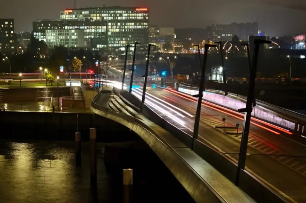 Illuminated bridge by buildings in city at night