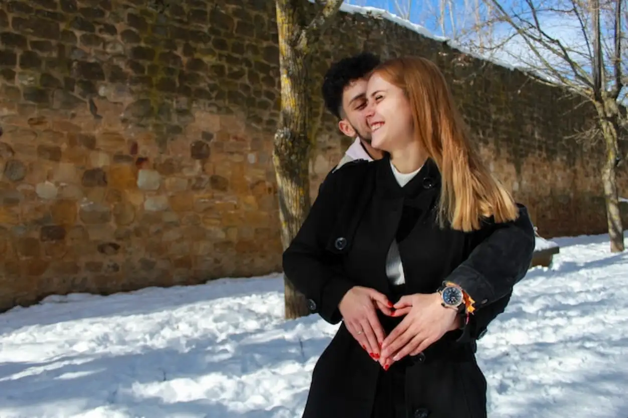 Happy interracial couple smiling in each other's arms on a snowy winter's day