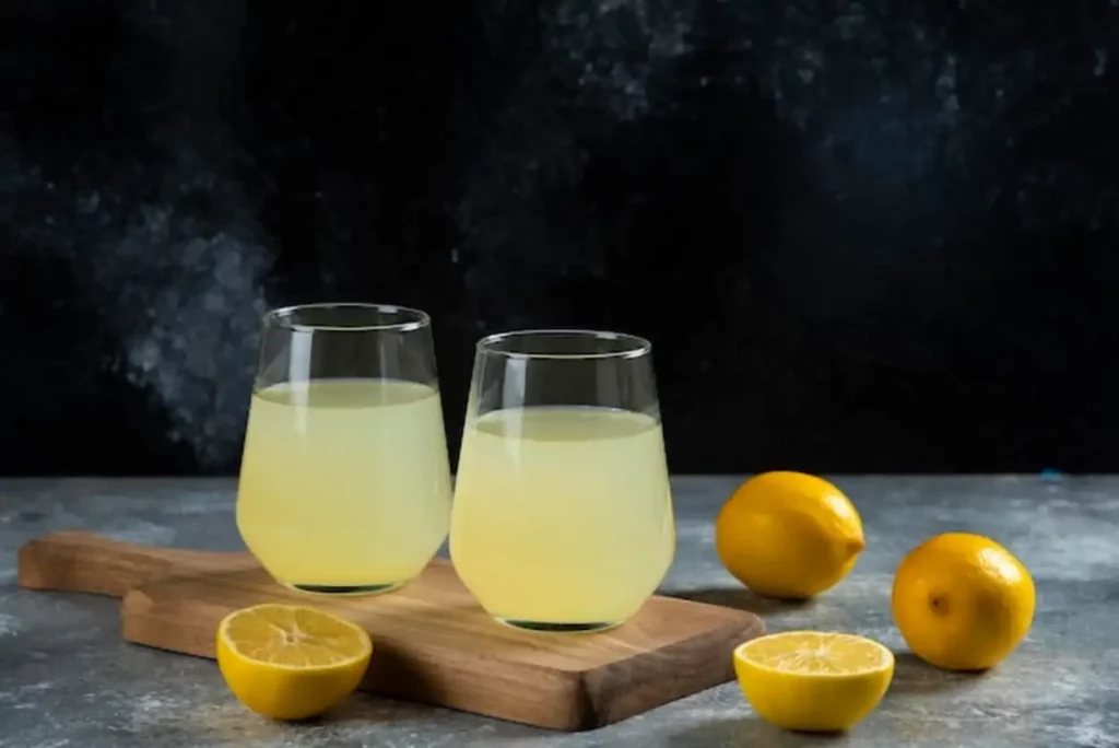 Two cups of lemon juice on wooden board.