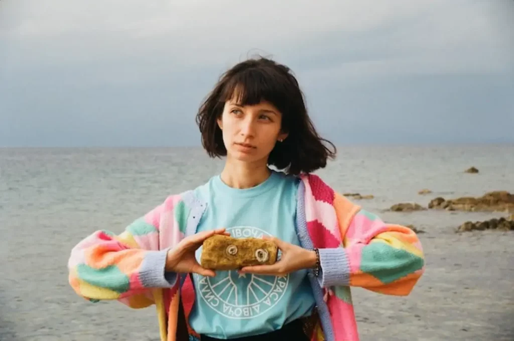 Woman holding rock standing against sea