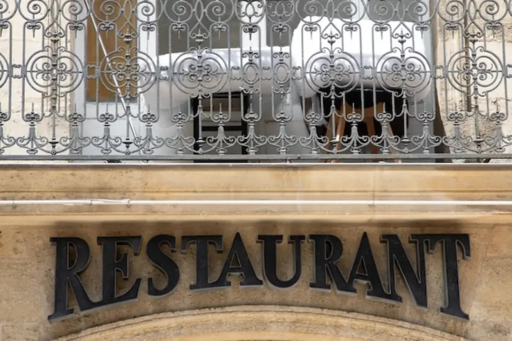 Old text restaurant sign on entrance facade wall signage