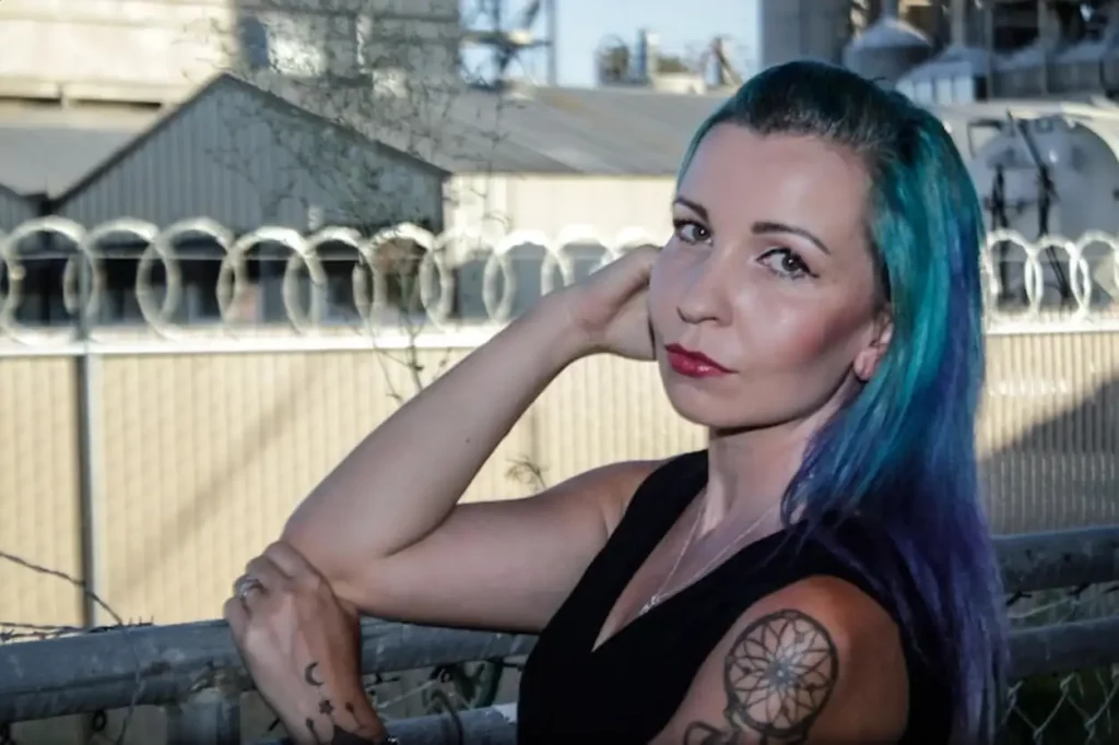 Portrait of young woman with green dyed hair while standing by fence