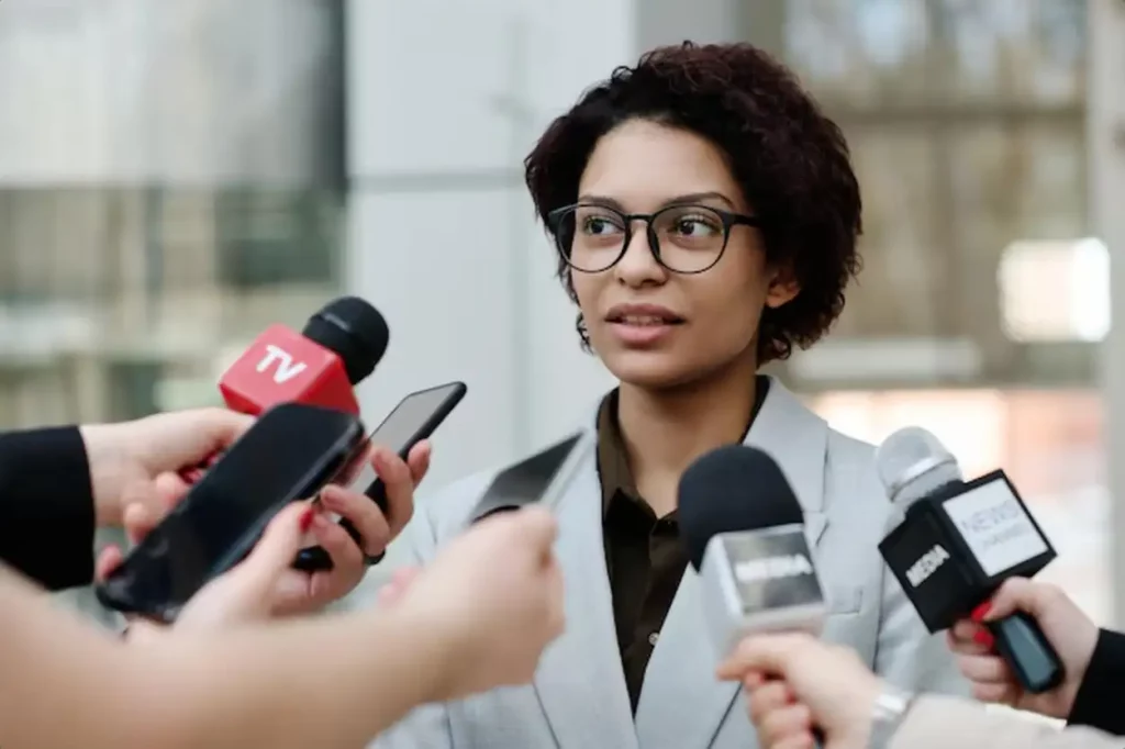 Young businesswoman in eyeglasses giving an interview at business conference she talking to reporter