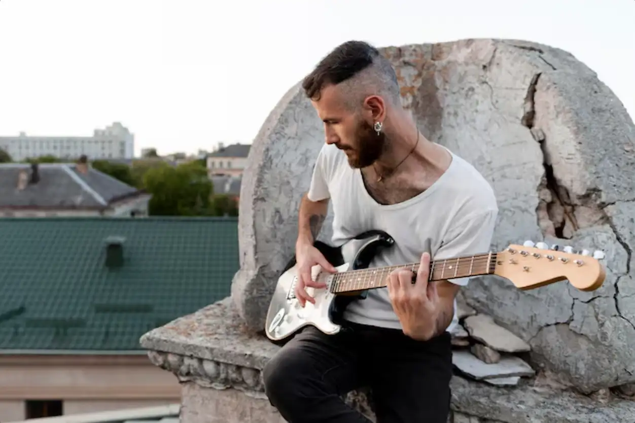 Male musician on roof top playing electric guitar