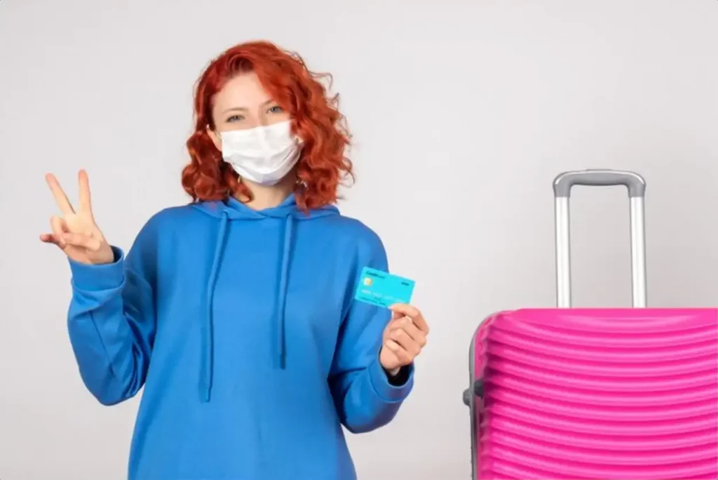 Front view female tourist holding bank card in mask