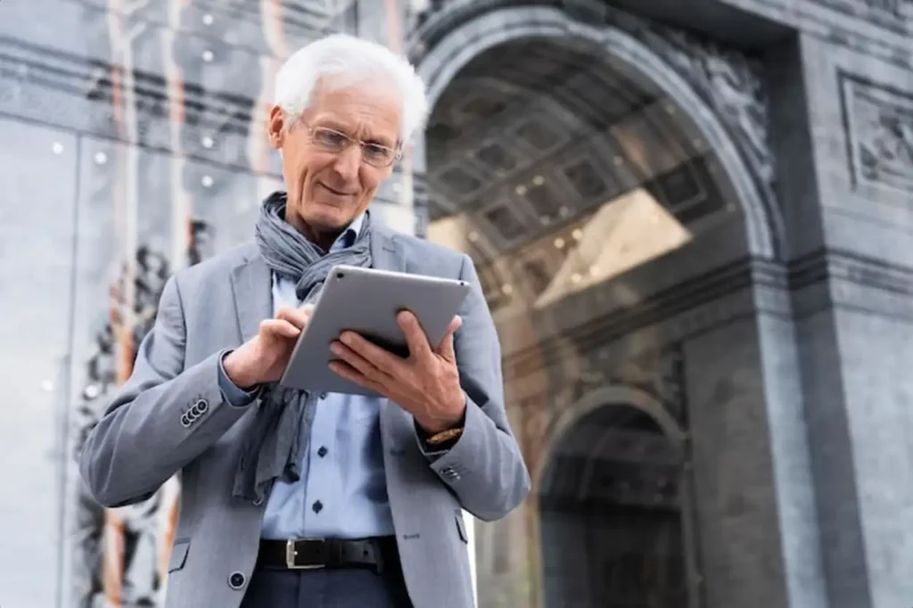 Stylish older man in the city using tablet
