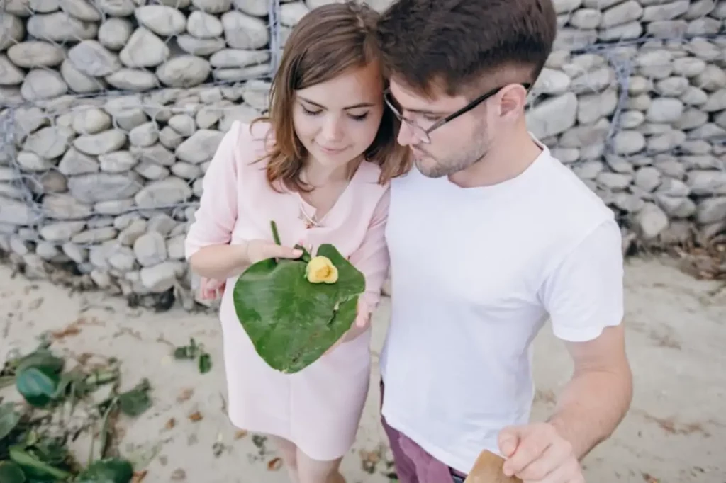 Couple holding a large leaf with a yellow flower