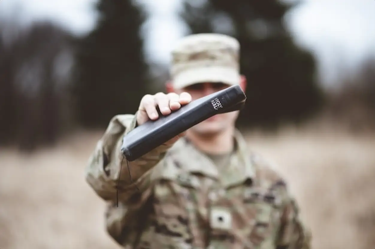 Selective focus shot of an American soldier holding the Holy Bible close to the camera