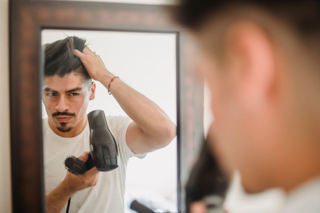Greffe de cheveux à Paris Homme qui se coiffe devant un miroir, soucieux de sa chevelure